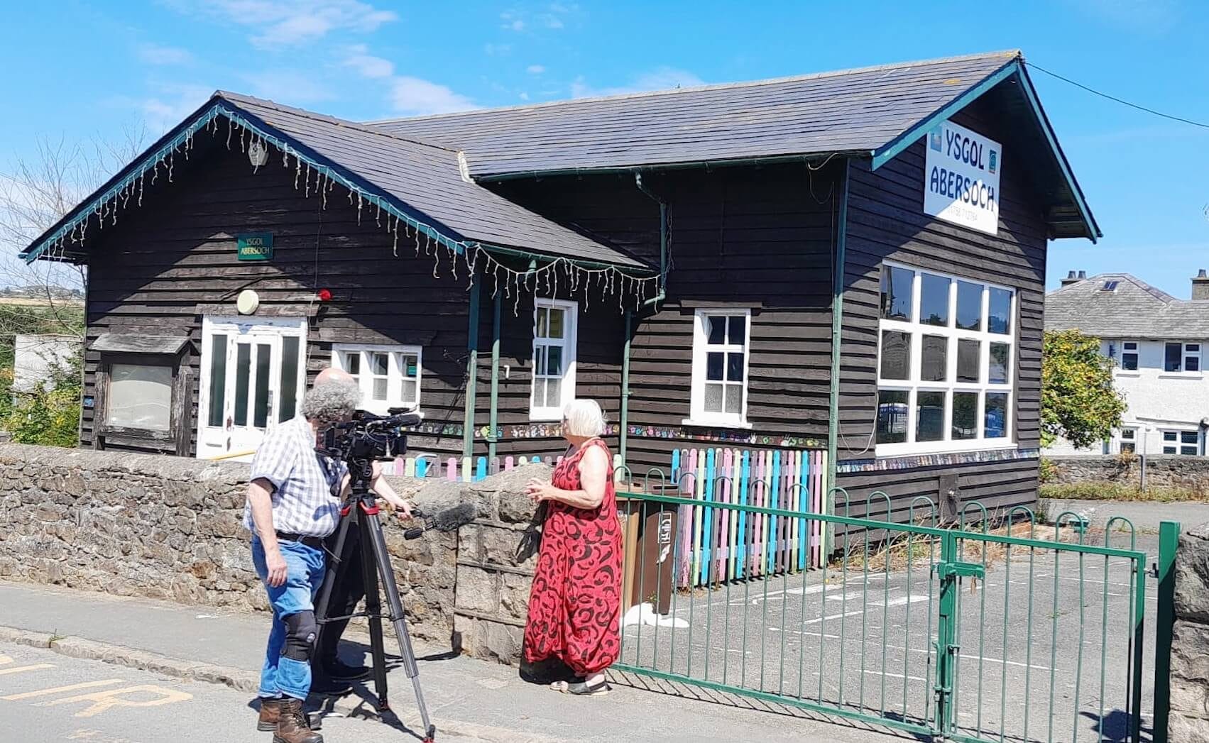A cameraman films a woman standing outside Abersoch hall